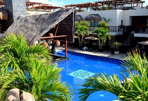 A swimming pool with a slide, surrounded by palm trees and a covered seating area. - Oceanfront @Mamitas Beach + Your Own Private Rooftop Paradise w/17' x 15' POOL (Playa del Carmen)