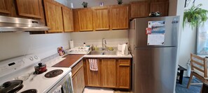 A kitchen with wooden cabinets, a stainless steel refrigerator, a stove, and a sink. - Luxury & homely Apartment. Close to Calgary airport, bus stop and shopping mall. (Airdrie)