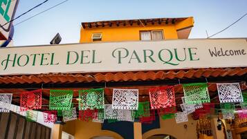 Un hotel llamado 'Hotel Del Parque' con un letrero de bienvenida y coloridos adornos de papel.
