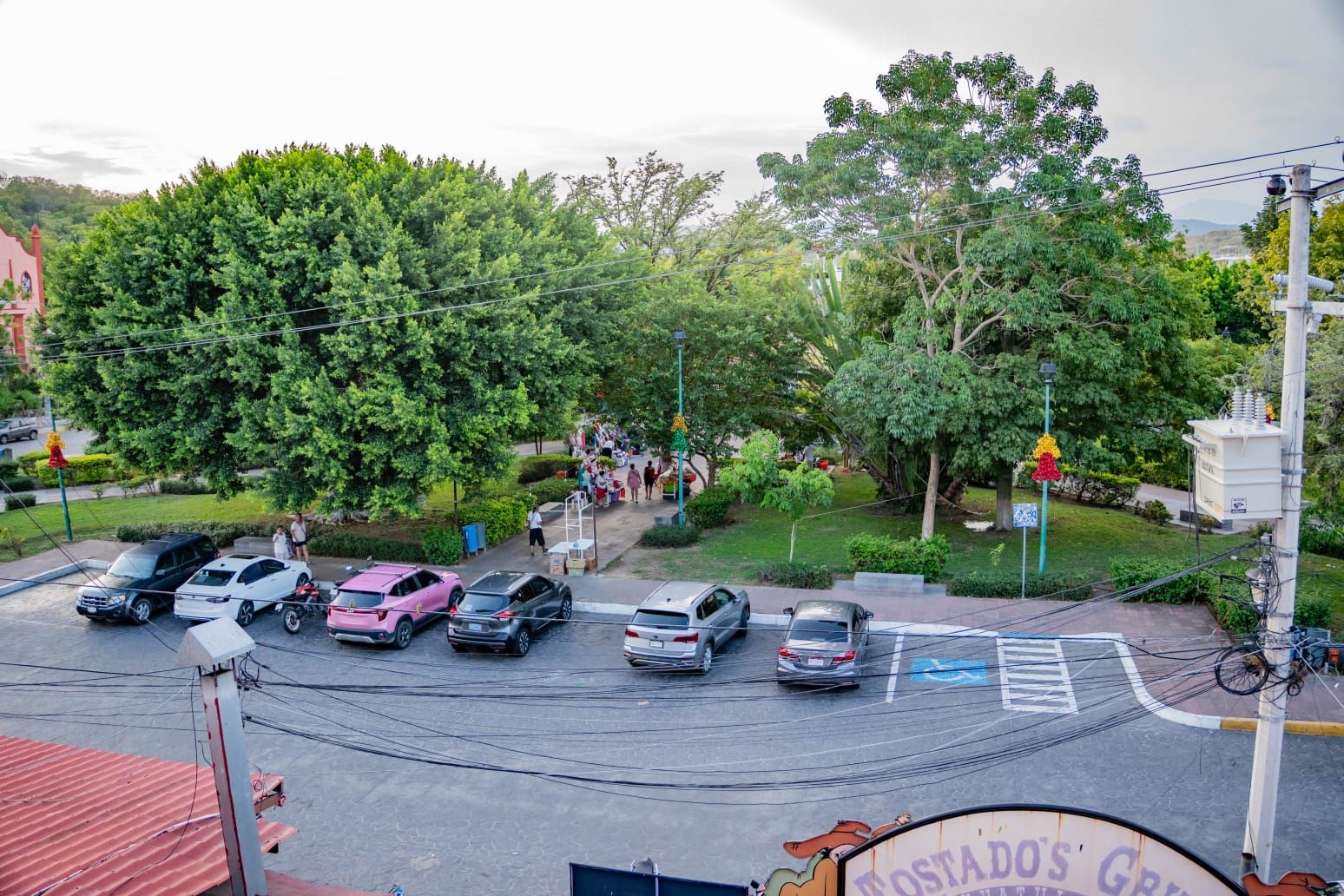 A parking lot with several cars, a pedestrian crossing, and a building with a sign that reads 'POSTADO'S GRILL'.