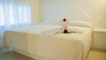 Una habitación de hotel con una cama bien hecha, una rosa roja y una decoración con forma de cisne blanco.