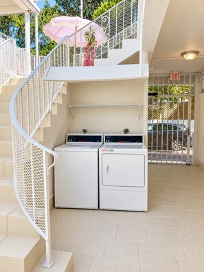 A laundry area with two washing machines, a metal spiral staircase, and a gated exit. - #14 – Cozy & Functional Studio w/Queen Bed, Work Desk, Kitchen and Free Parking (Miami)