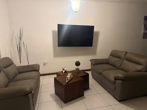 Una sala de estar con dos sofás, una mesa de centro, un televisor de pantalla plana y objetos decorativos.