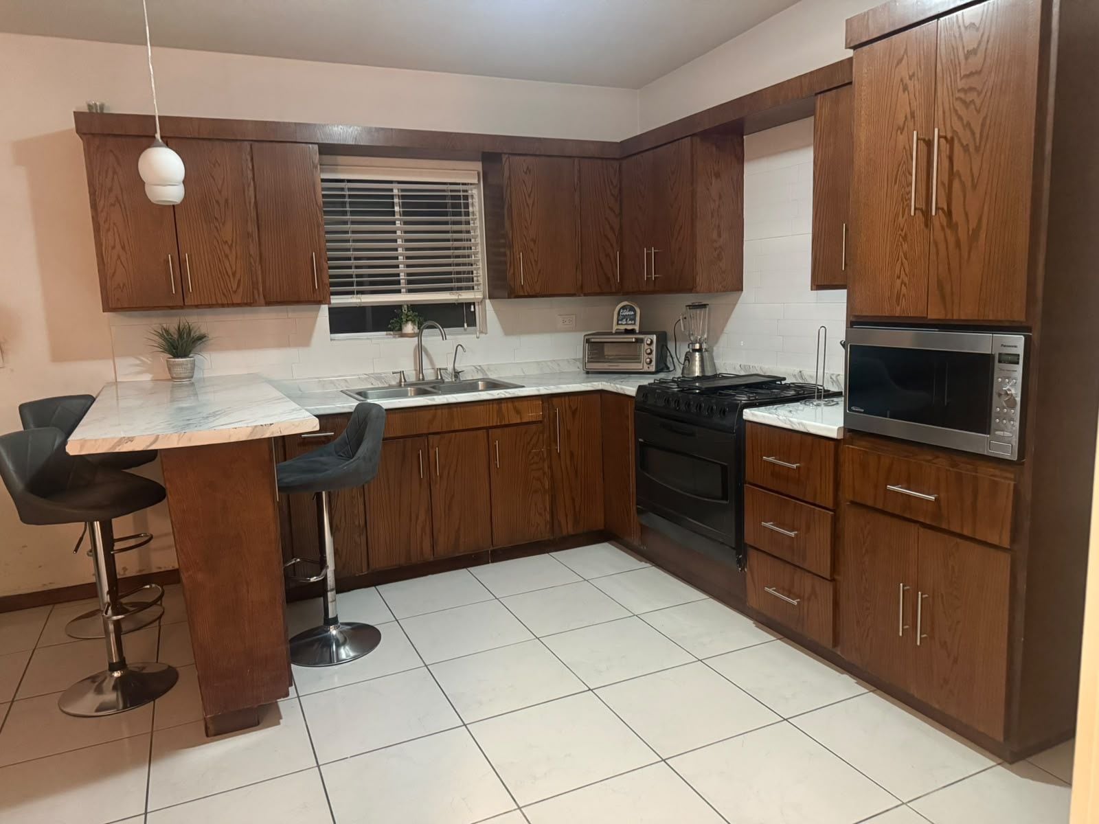 Una cocina con armarios de madera, estufa, microondas y un lavamanos.