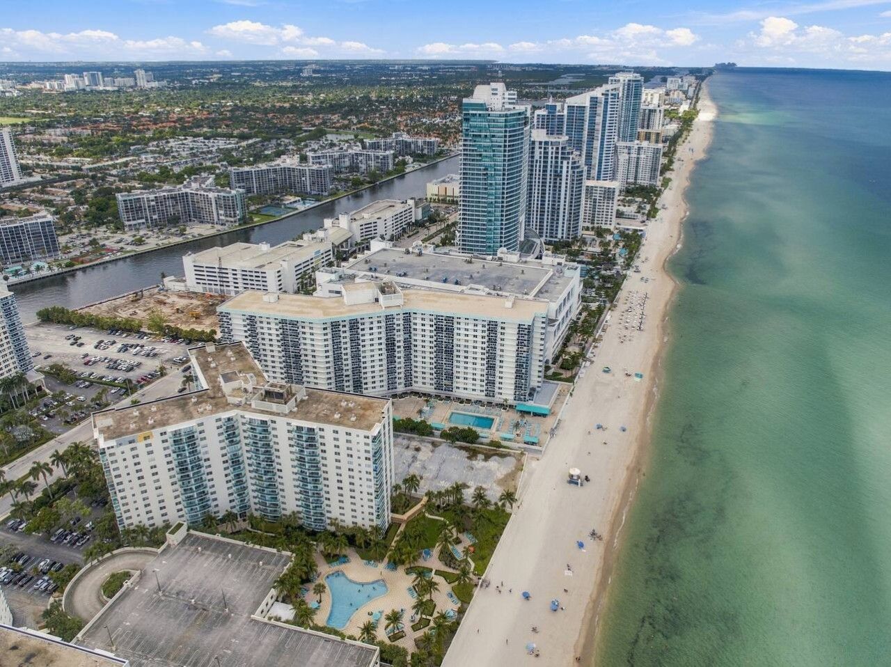 A coastal residential area with high-rise buildings, a beach, and a river.