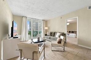 A modern living room with a flat-screen TV, a sofa, a coffee table, and a chair. - Modern 2-bedroom apartment at the Tides Beach (Hollywood)