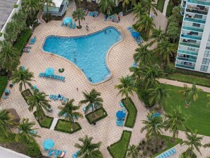 Un espace piscine comprenant plusieurs piscines, des chaises longues et des palmiers.