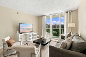 A modern living room with a television, sofa, and a glass coffee table. - Modern 2-bedroom apartment at the Tides Beach (Hollywood)