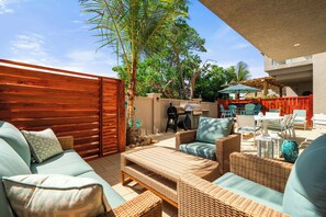 A patio with wicker furniture, a wooden fence, and a barbecue area. - Walk-Out to Pool |Jacuzzi, BBQ & White Sand Lounge (Noord)