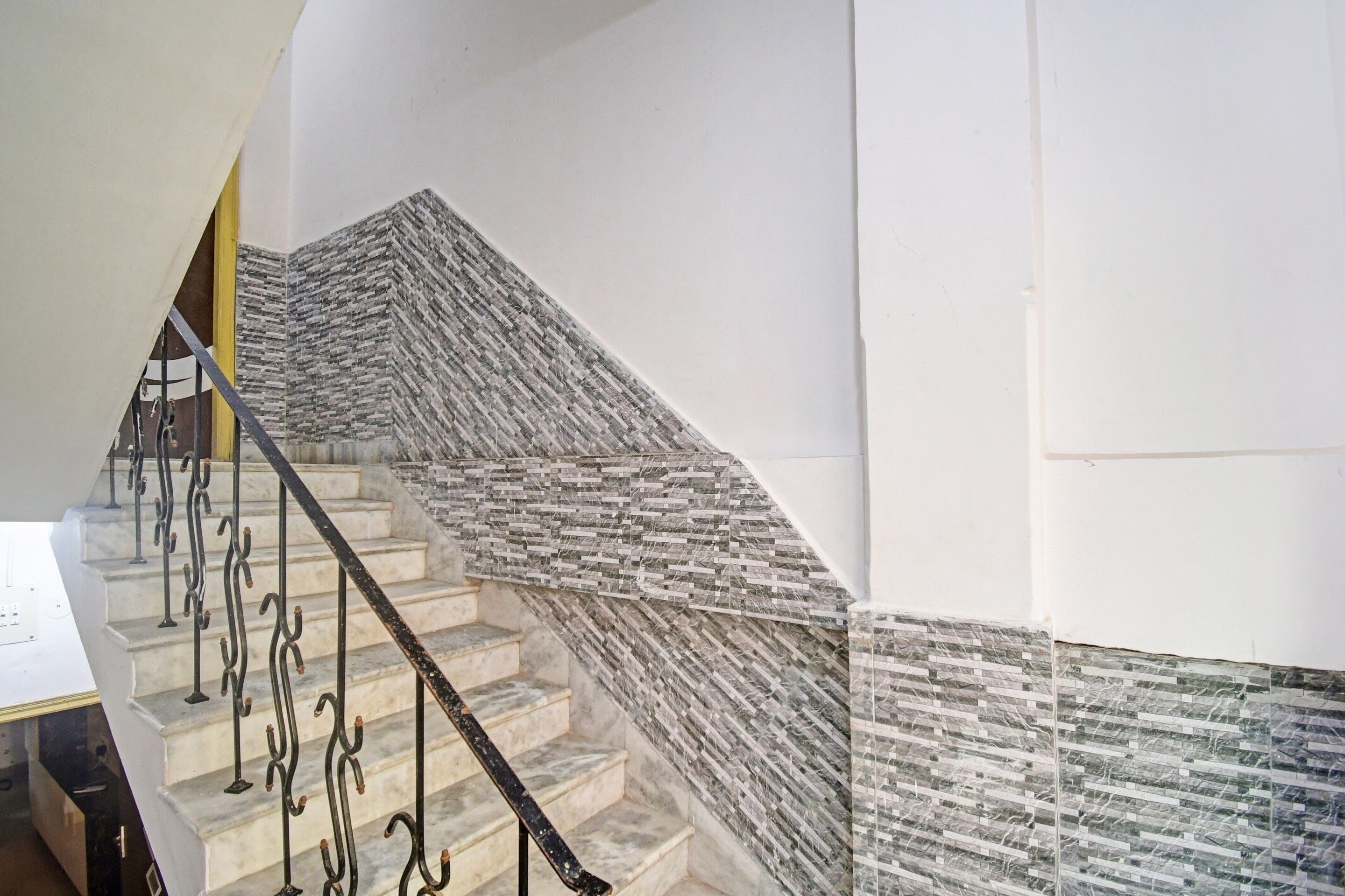 A staircase with a unique textured wall design and a metal handrail.