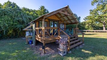 Une cabane en bois dotée d’un porche, d’une terrasse couverte et d’un petit jardin.