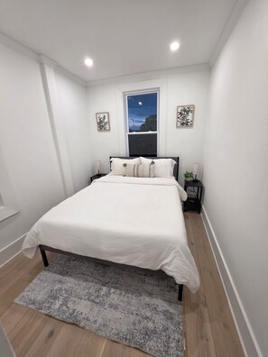 Une chambre à coucher avec un lit, une fenêtre, une table de chevet et un tapis.