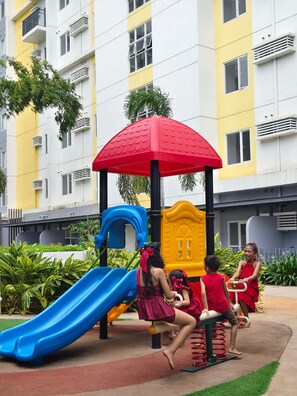 A children's play area with a slide, climbing structure, and a red shelter. - Ground Floor Studio with Patio and Pool View at Casa Mira Towers, Mandaue (Mandaue)