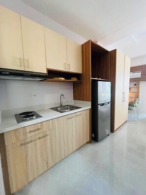 A modern kitchen with a built-in stove, sink, and a large refrigerator. - Ground Floor Studio with Patio and Pool View at Casa Mira Towers, Mandaue (Mandaue)
