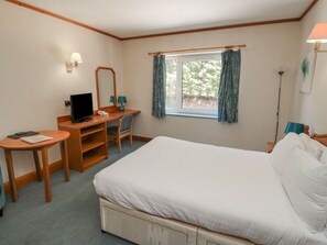 A hotel room with a bed, a desk with a computer, a chair, a small table, and a window with curtains. - Sycamore (Newton Abbot)