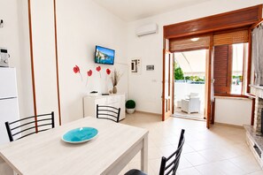 A modern kitchen with a dining table, chairs, and a TV mounted on the wall. - Apartment with a spacious outdoor area in the center of Santa Maria di Leuca (Santa Maria di Leuca)