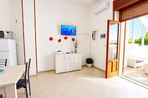 Eine moderne Küche mit Essbereich, einem an der Wand befestigten Fernseher und einer Glastür zum Außenbereich.