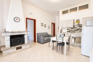 Eine moderne Küche mit Essbereich, Kamin und einem Wohnzimmer mit Sofa.