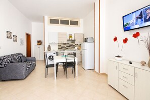 Ein kompakter Wohnbereich mit Küchenzeile, Essbereich und einer Couch.