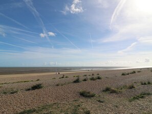 Ein Kiesstrand bei strahlend blauem Himmel und weiter Fernsicht.