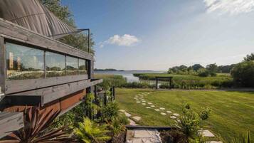 A modern house with a large glass window overlooking a lake.