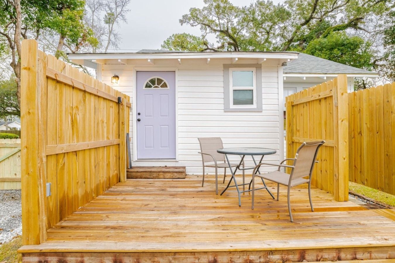 A wooden deck with a door, a small table, and two chairs.