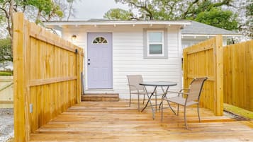 A wooden deck with a door, a small table, and two chairs.