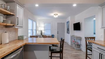 A modern kitchen with a central island, wooden countertops, and built-in appliances.