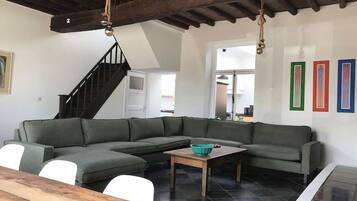 Een moderne woonkamer met een hoekbank, een houten salontafel en een trap.