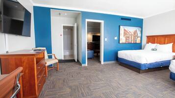 A hotel room with a bed, a desk, a chair, and a television.
