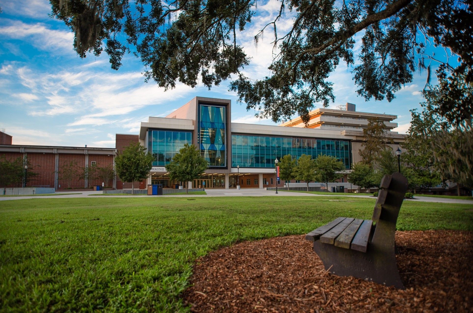 A modern building with a glass facade, surrounded by a well-maintained grassy area and trees.