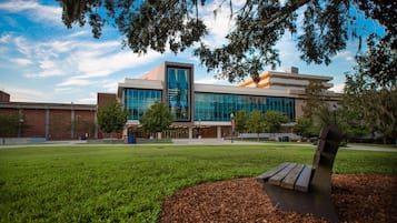 A modern building with a glass facade, surrounded by a well-maintained grassy area and trees.