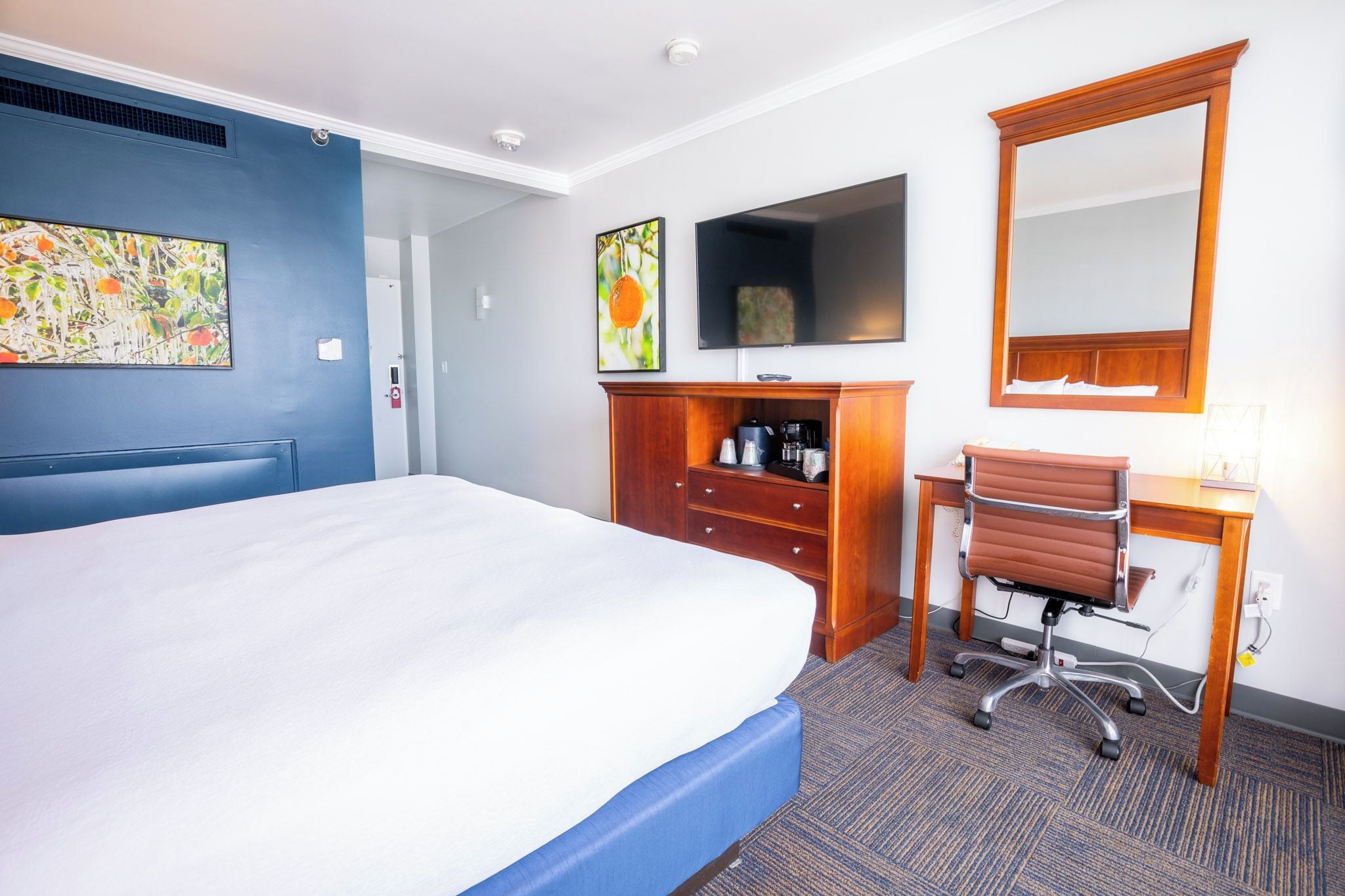 Une chambre d’hôtel comprenant un lit, un bureau, une chaise, une télévision et un miroir.