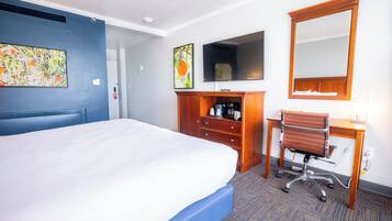 Une chambre d’hôtel comprenant un lit, un bureau, une chaise, une télévision et un miroir.