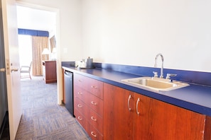 Una kitchenette compacta con un lavamanos, un refrigerador pequeño y una encimera.