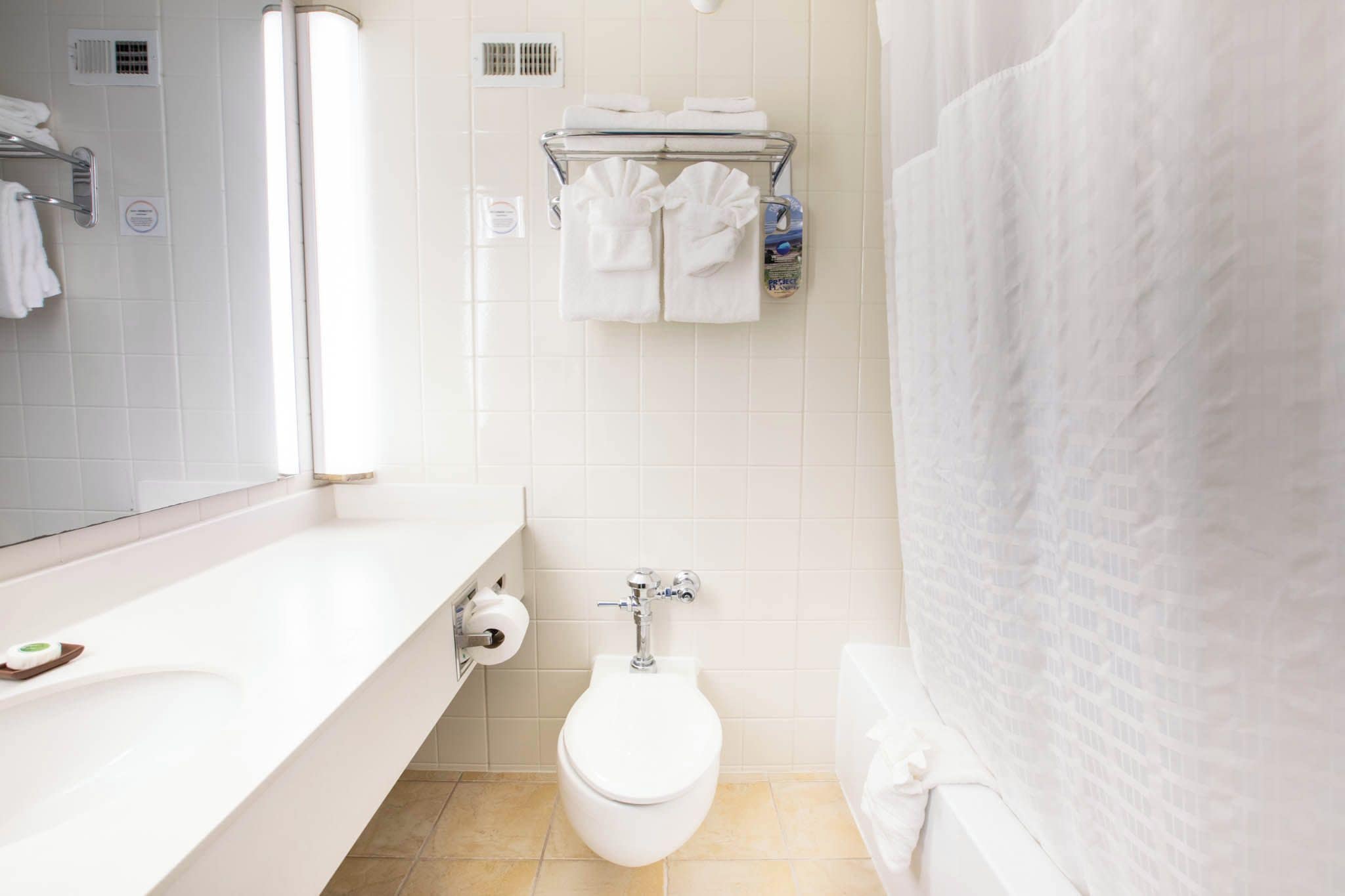 Un baño moderno con inodoro, toallero y espejo.