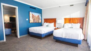 Ein Hotelzimmer mit zwei Betten, einem Schreibtisch, einem Stuhl, einem Fernseher und einem Bild an der Wand.