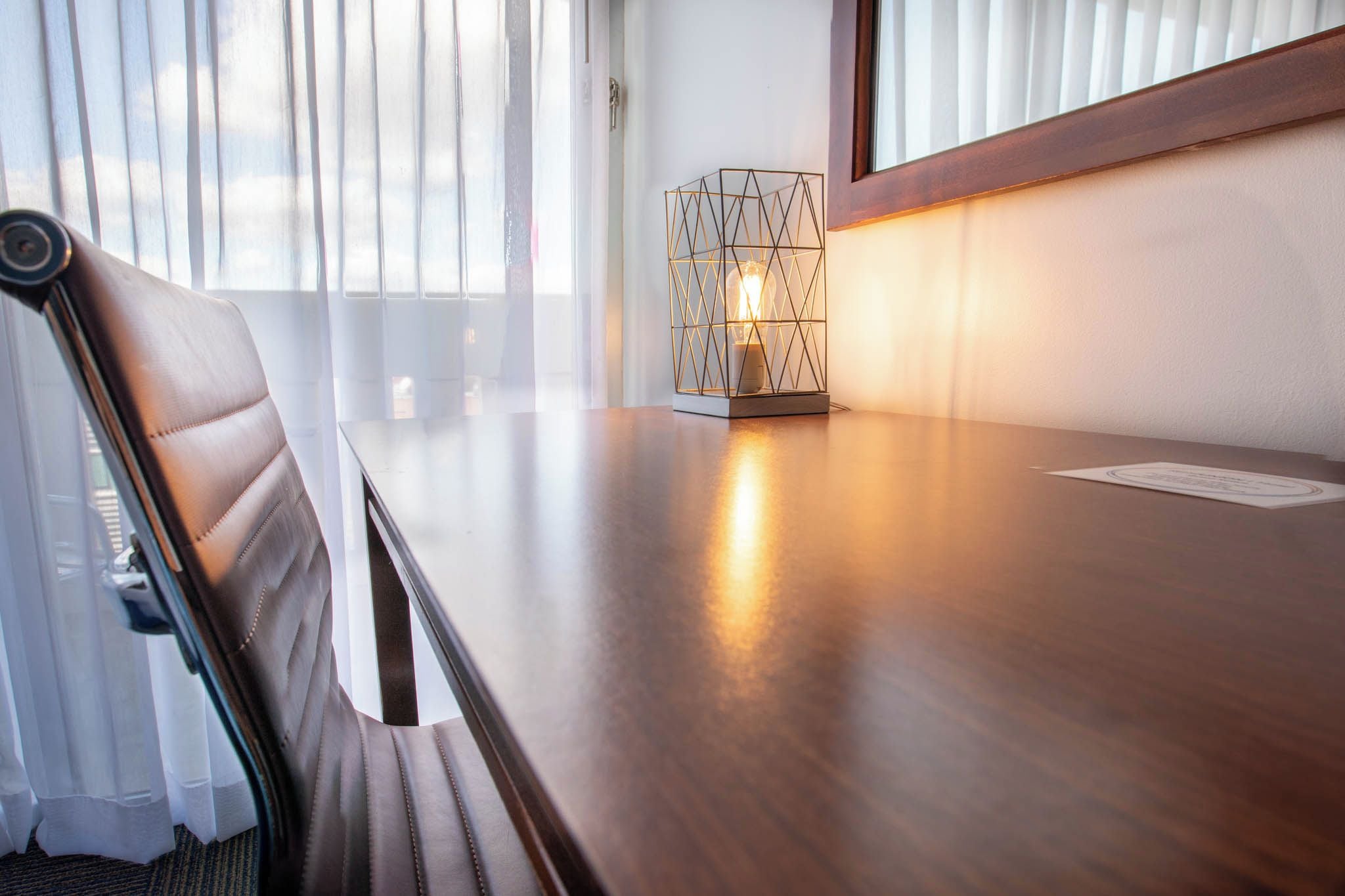 Una mesa de conferencias con una silla, una lámpara geométrica y una ventana con persianas.