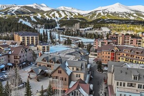 Uma cidade montanhosa com edifícios, uma estação de esqui e picos cobertos de neve.