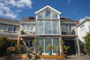 Ein zweigeschossiges Haus mit großer Glasschaufensterfront, einem Balkon im Obergeschoss und einer Garage.