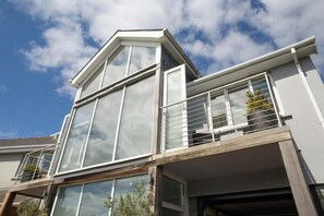 A modern two-story building with large windows, a balcony with a metal railing, and a garage entrance. - The Gallery, Tenby - Two Bedroom Cottage, Sleeps 4 (Tenby)
