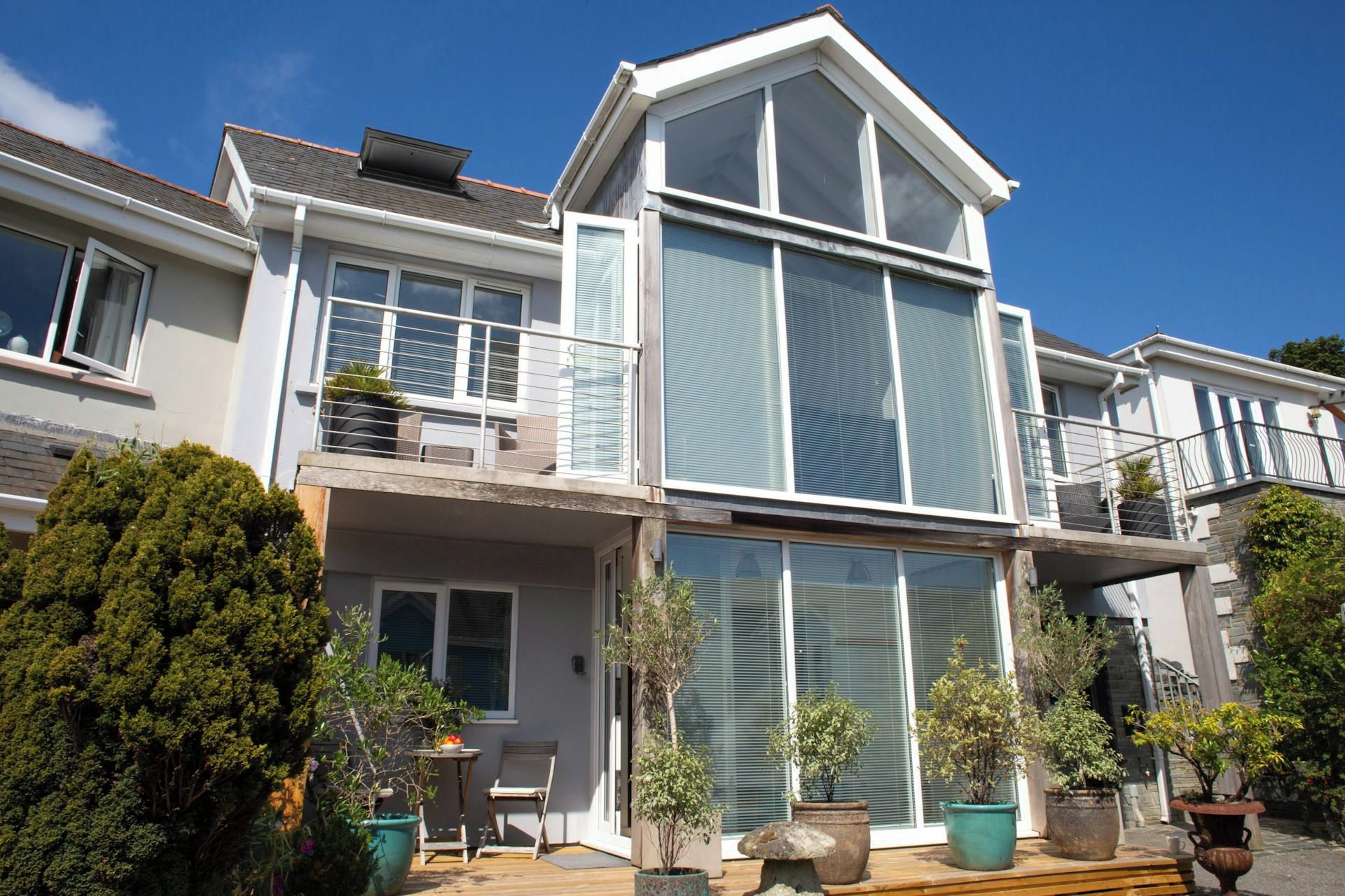 Un edificio residencial de dos plantas con un balcón y ventanas amplias.