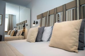 A hotel room with a large bed, a mirror, and a wall-mounted light fixture. - The Gallery, Tenby - Two Bedroom Cottage, Sleeps 4 (Tenby)