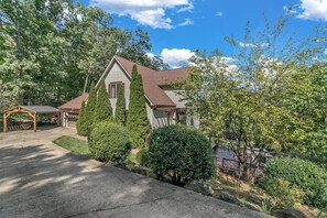 A two-story house with a sloped roof, surrounded by trees and a paved driveway. - Unique Home with Magnificent Views, Walkable  to Golf Course and Town of BM (Black Mountain)