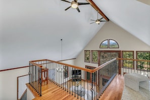 A spacious loft with a high ceiling, wooden staircase, and large windows offering views of the outdoors. - Unique Home with Magnificent Views, Walkable  to Golf Course and Town of BM (Black Mountain)