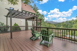 A wooden deck with two green Adirondack chairs, a pergola, and a view of a mountain range. - Unique Home with Magnificent Views, Walkable  to Golf Course and Town of BM (Black Mountain)