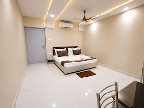 A modern bedroom with a bed, bedside table, and a ceiling fan. - Hotel The Pearl (Bhubaneswar)