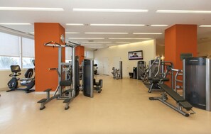 Un gimnasio con diversos equipos de ejercicio, incluyendo cintas de correr, máquinas de pesas y una bicicleta estática.