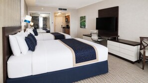 Habitación de hotel con una cama grande, un escritorio, un televisor de pantalla plana y un espejo.