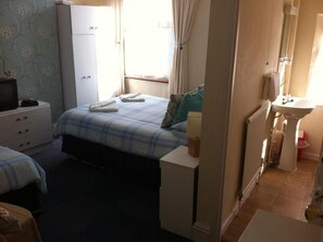 A bedroom with a bed, a dresser, a bedside table, and a window with curtains. - Seahaven House (Ryde)